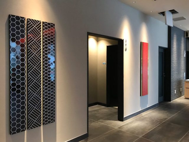 伝統紋様をレーザー加工で表現した艶のある黒い3連パネル。ホテルのロビーに設置された壁面装飾。