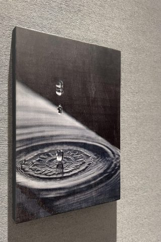 水滴が落ちて波紋が広がる瞬間のモノトーンの木製プリントパネル。スパのに設置された壁面装飾。